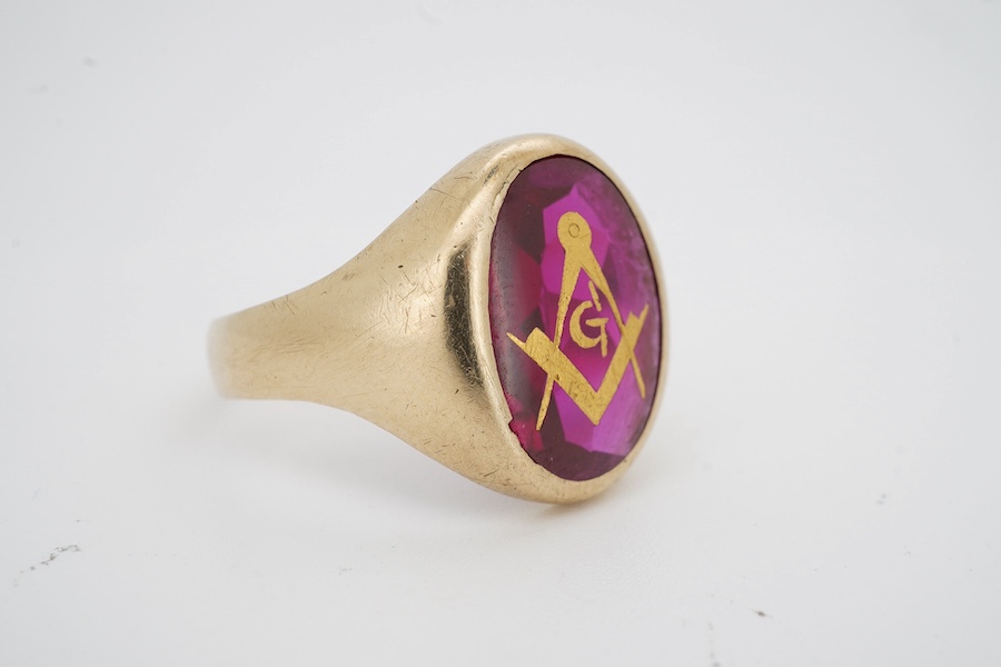 A 9ct and synthetic ruby set signet ring, the stone carved with gilded masonic symbol, size S/T, gross weight 5.8 grams. Condition - fair to good